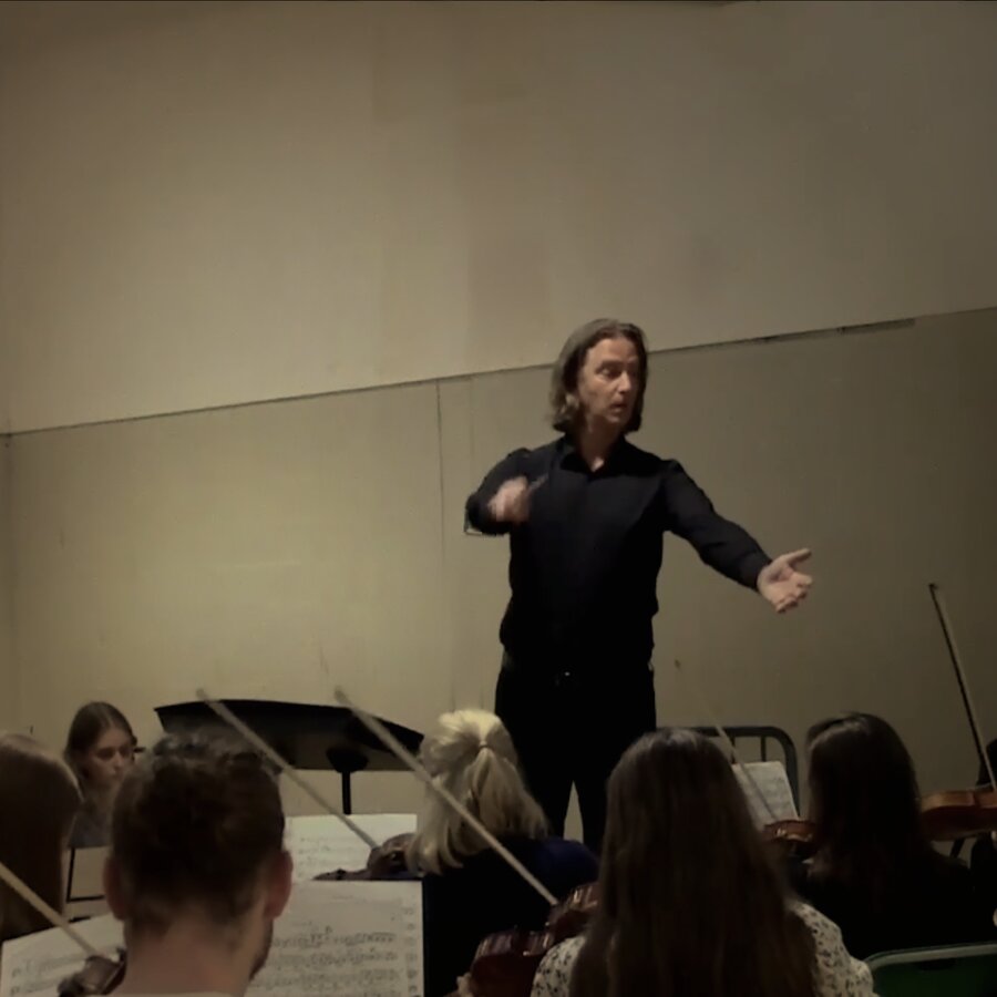Andrew Spoeth conducting, arms open to the full ensemble
