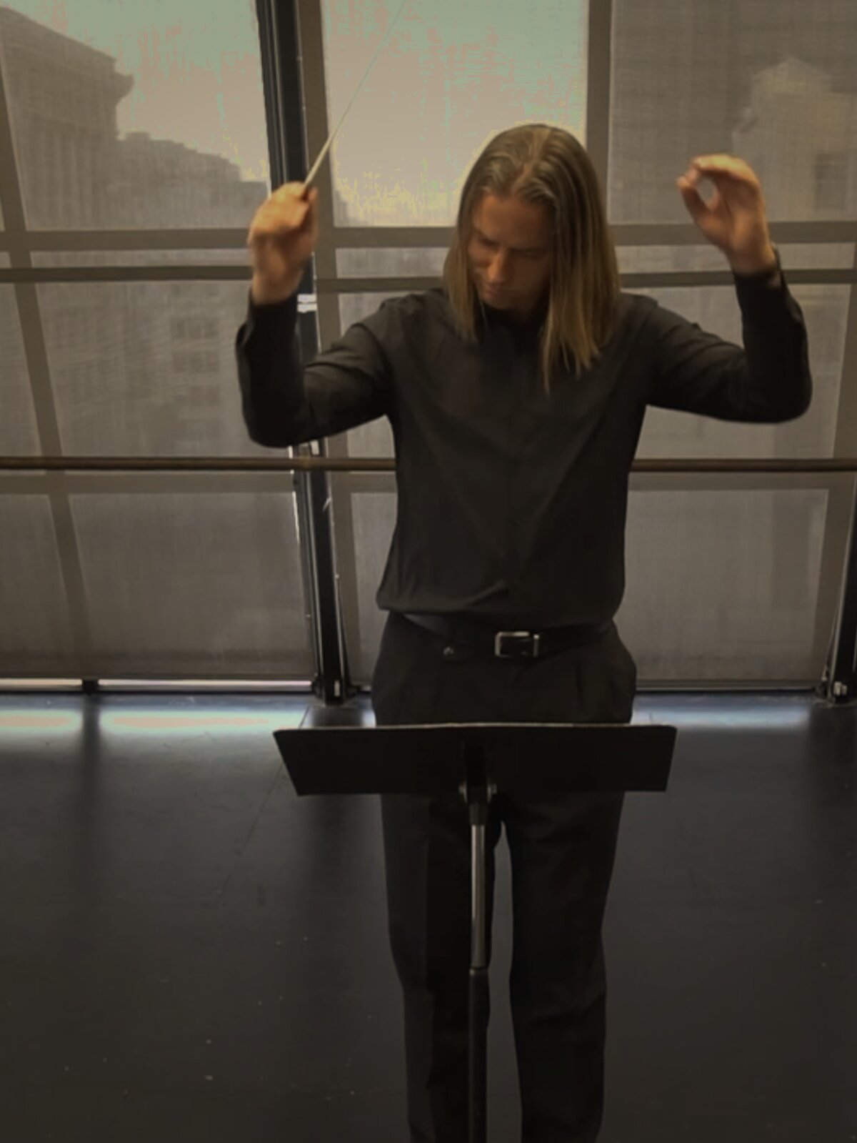Andrew Spoeth conducting, baton raised, in a San Francisco studio
